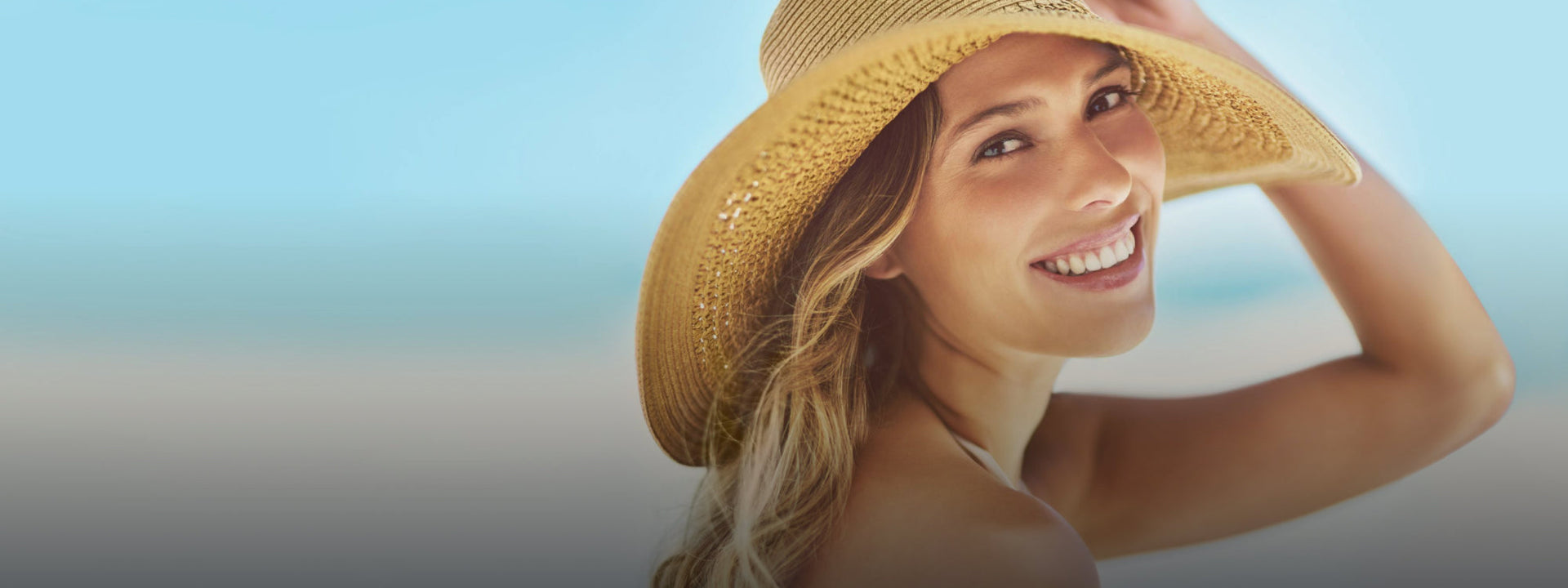 Frau mit Sonnenhut am Strand ist glücklich